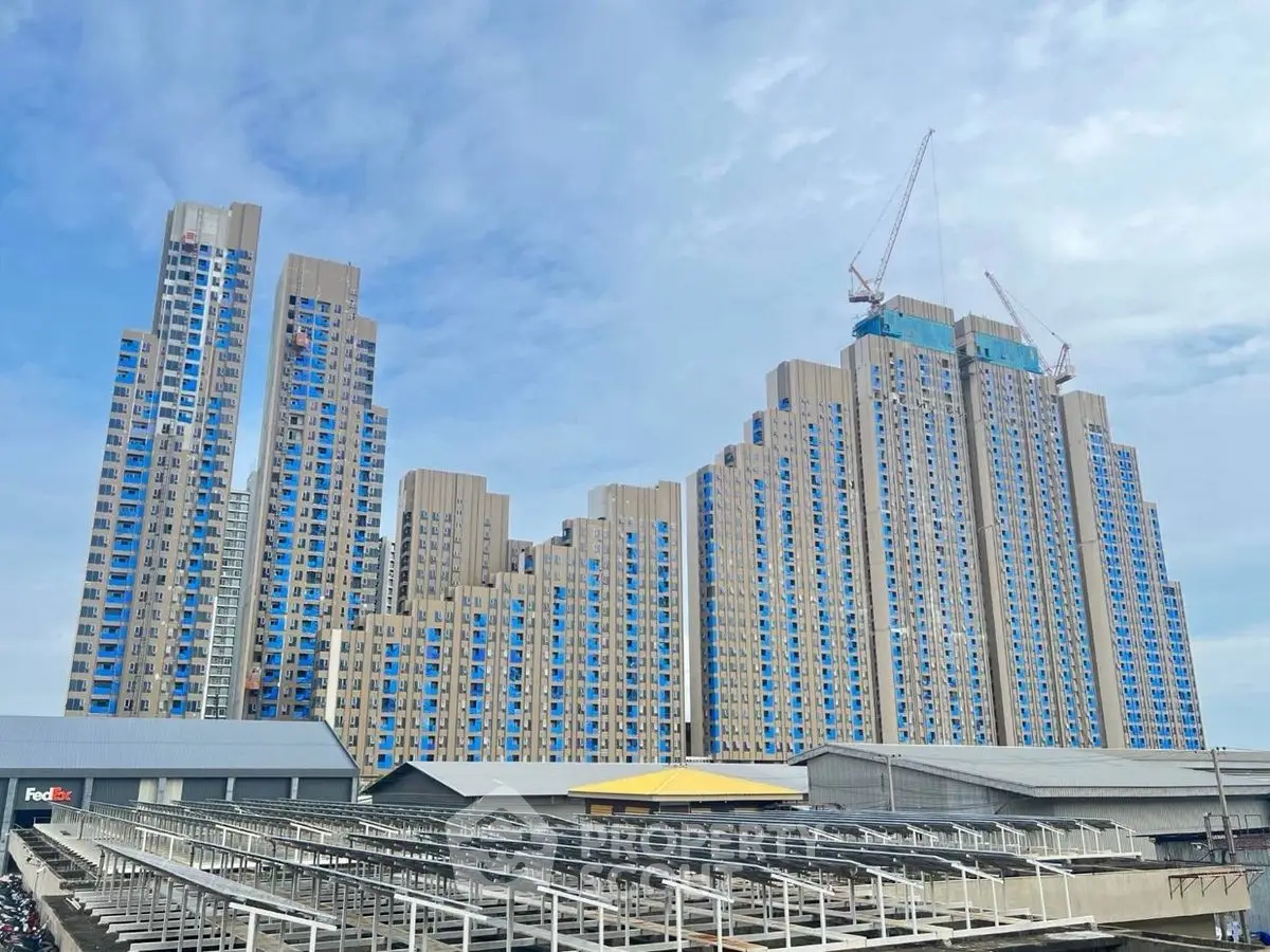 Stunning modern high-rise building with unique architectural design and cranes on top, under a clear blue sky.