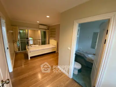Spacious bedroom with ensuite bathroom and wooden flooring in modern apartment