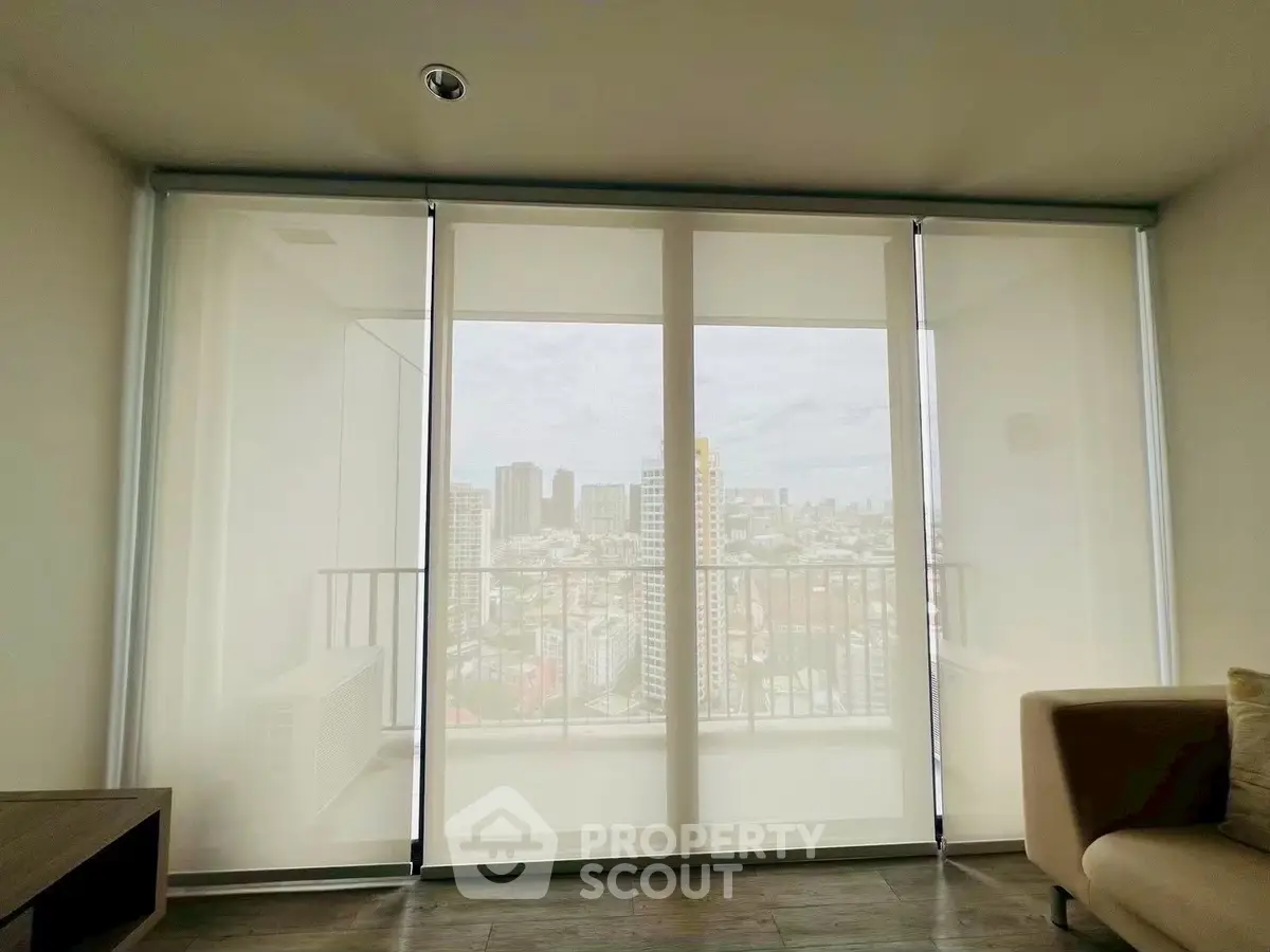 Spacious living room with floor-to-ceiling windows offering a stunning city view.