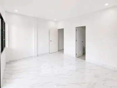 Spacious empty room with marble flooring and white walls, perfect for customization.