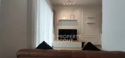 Modern living room with stylish decor and large TV, featuring elegant wall paneling and natural light.