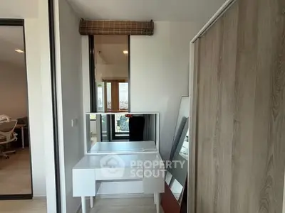 Modern bedroom with stylish vanity and large mirror, featuring sleek design and natural light.