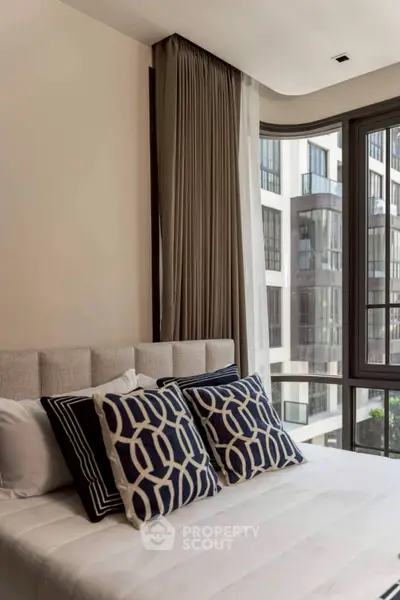 Modern bedroom with stylish decor and large windows offering a stunning city view.