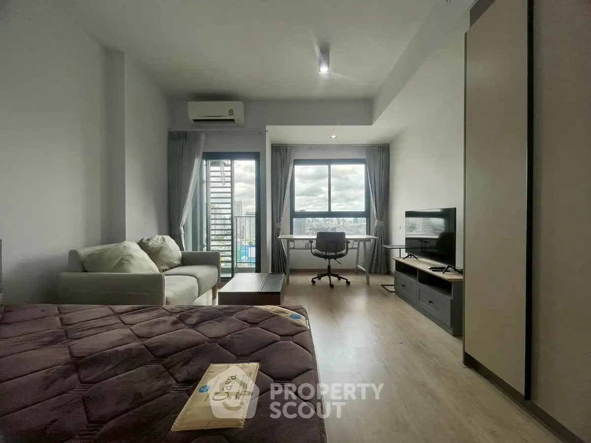 Modern studio apartment with city view, featuring cozy living area and workspace.
