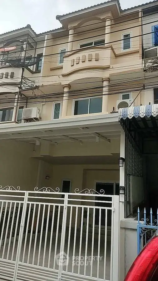 Elegant three-story townhouse with gated entrance and balcony, perfect for urban living.