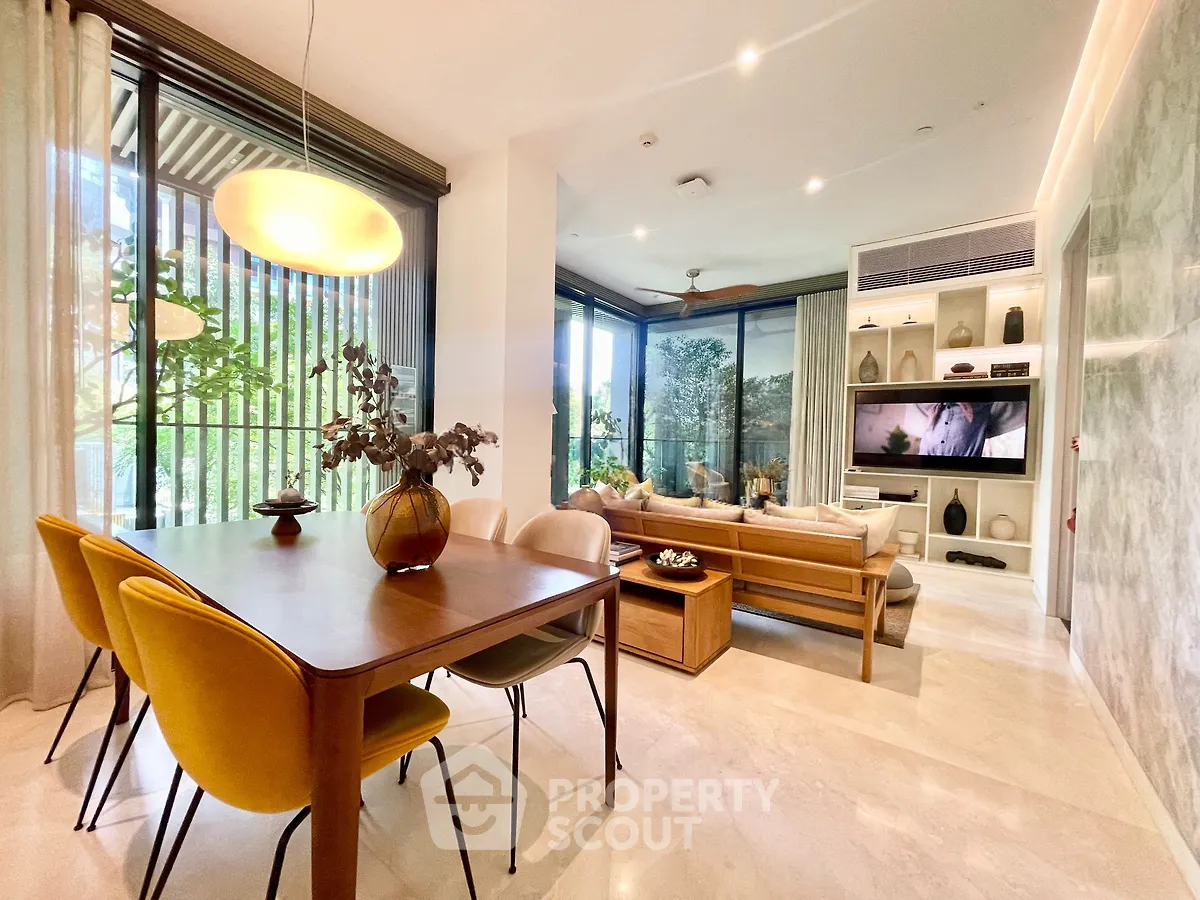 Luxurious open-plan living and dining area with modern decor and large windows offering a serene garden view.