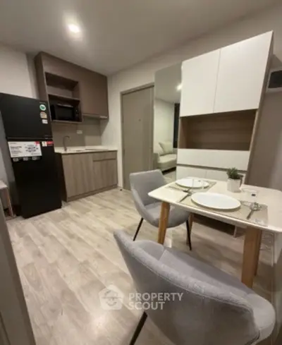 Modern kitchen with dining area in stylish apartment, featuring sleek cabinetry and contemporary furnishings.