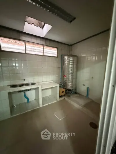 Spacious utility room with tiled walls and water tank, ideal for laundry or storage.