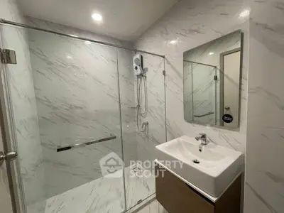 Modern bathroom with glass shower and sleek sink in elegant marble design.