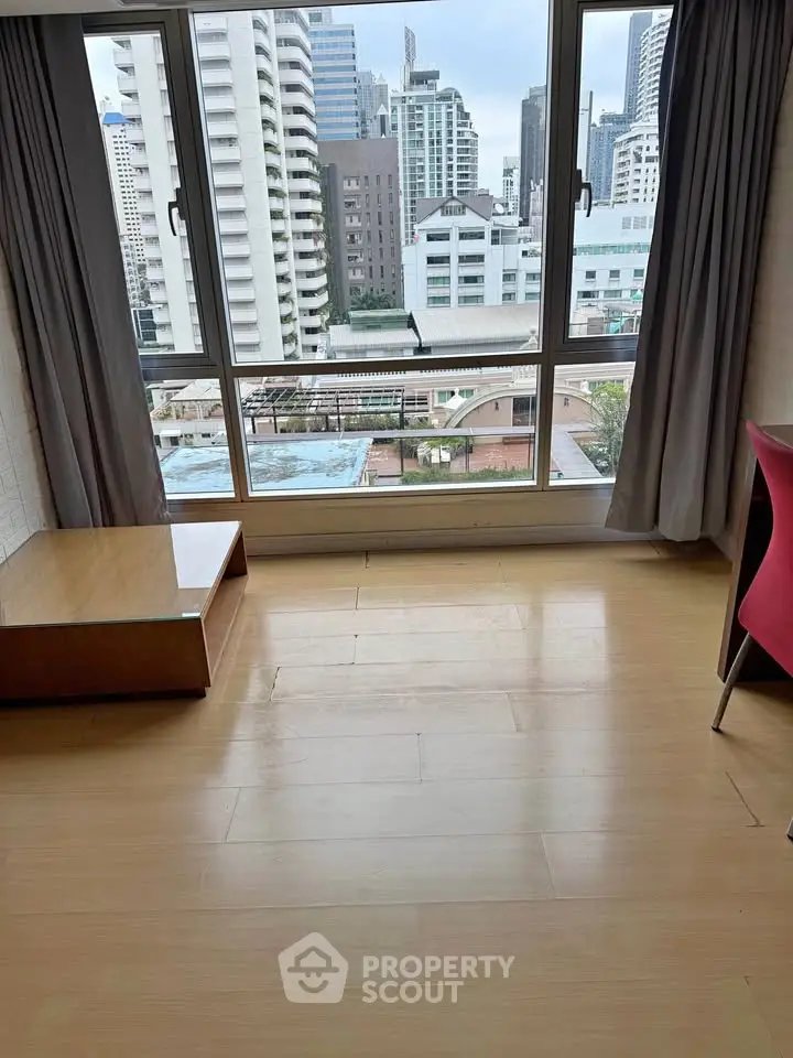Spacious room with large window offering stunning city view in modern apartment.
