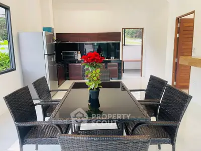 Modern dining area with wicker furniture and sleek kitchen in open layout