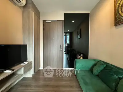 Modern living room with green sofa and wall-mounted TV, featuring stylish wooden flooring and elegant decor.