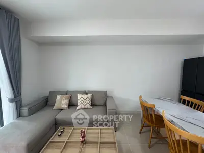 Modern living room with stylish gray sofa, wooden dining set, and elegant decor in a bright, open space.