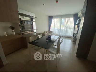 Modern living room with dining area and large window, featuring stylish furniture and natural light.