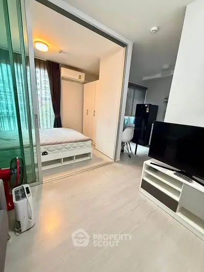 Modern apartment interior with bedroom and living area, featuring sleek design and natural light.