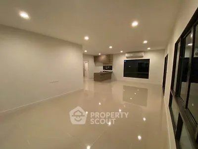 Spacious open-plan living room with modern kitchen and sleek tile flooring.