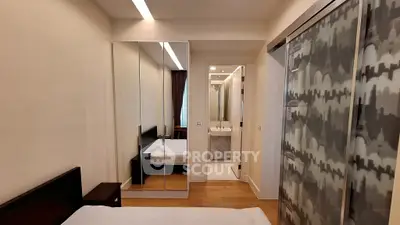 Modern bedroom with mirrored wardrobe and ensuite bathroom in stylish apartment.