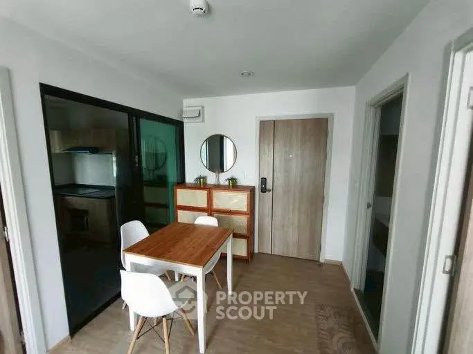 Modern dining area with wooden table and chairs, adjacent to a sleek kitchen with glass sliding doors.