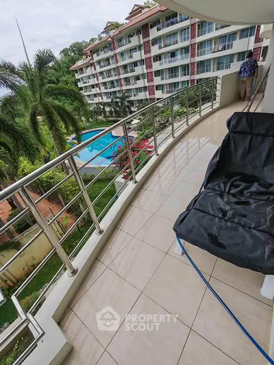 Spacious balcony with pool view in a modern apartment complex, perfect for relaxation and outdoor enjoyment.