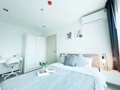 Modern bedroom with stylish decor and natural light, featuring a cozy bed and workspace.