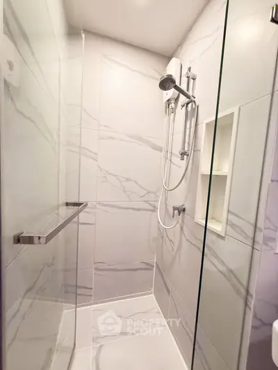 Modern bathroom shower with sleek marble tiles and built-in shelving