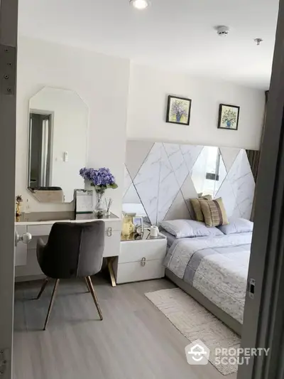 Modern bedroom with stylish decor, featuring a cozy bed, elegant vanity, and chic wall art.