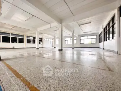 Spacious industrial-style open space with large windows and polished concrete floors.