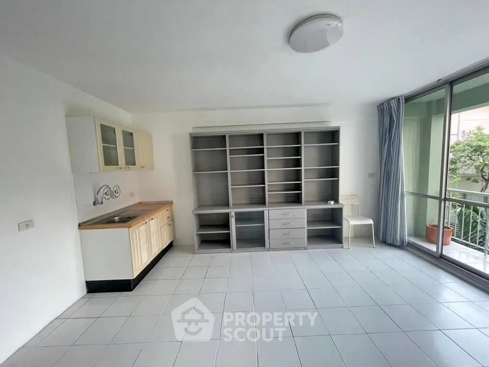 Spacious living area with built-in shelving and balcony access in modern apartment.