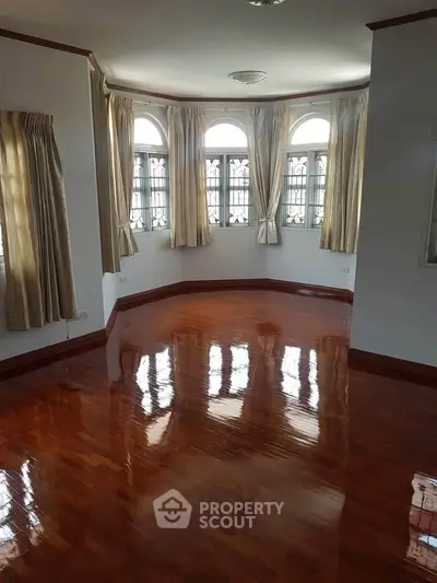 Spacious room with polished hardwood floors and elegant arched windows.