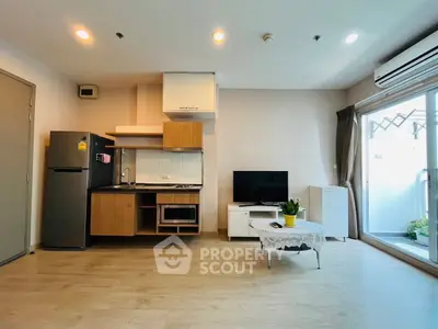 Modern open-layout living room with kitchen, featuring sleek appliances and natural light.