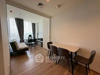 Modern apartment with open living and dining area featuring stylish furniture and large windows.