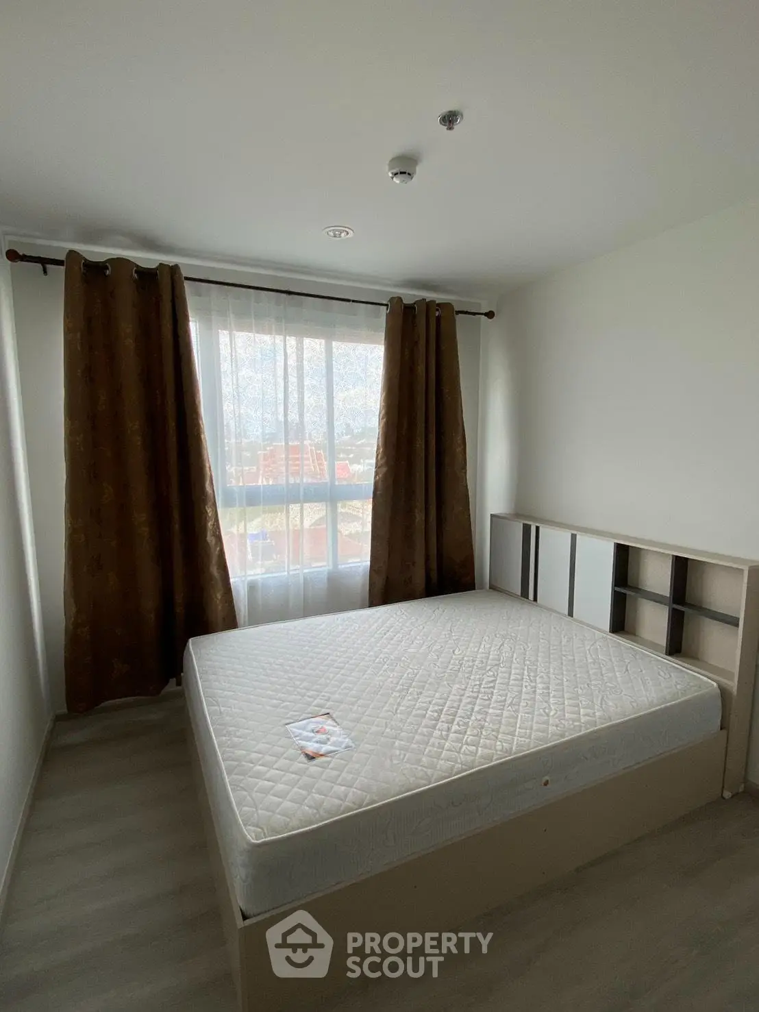 Spacious bedroom with large window and natural light, featuring a comfortable bed and modern decor.