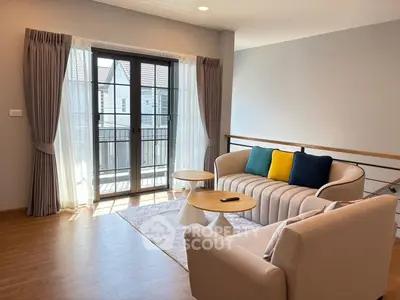 Bright living room with modern furniture and large windows opening to a balcony.