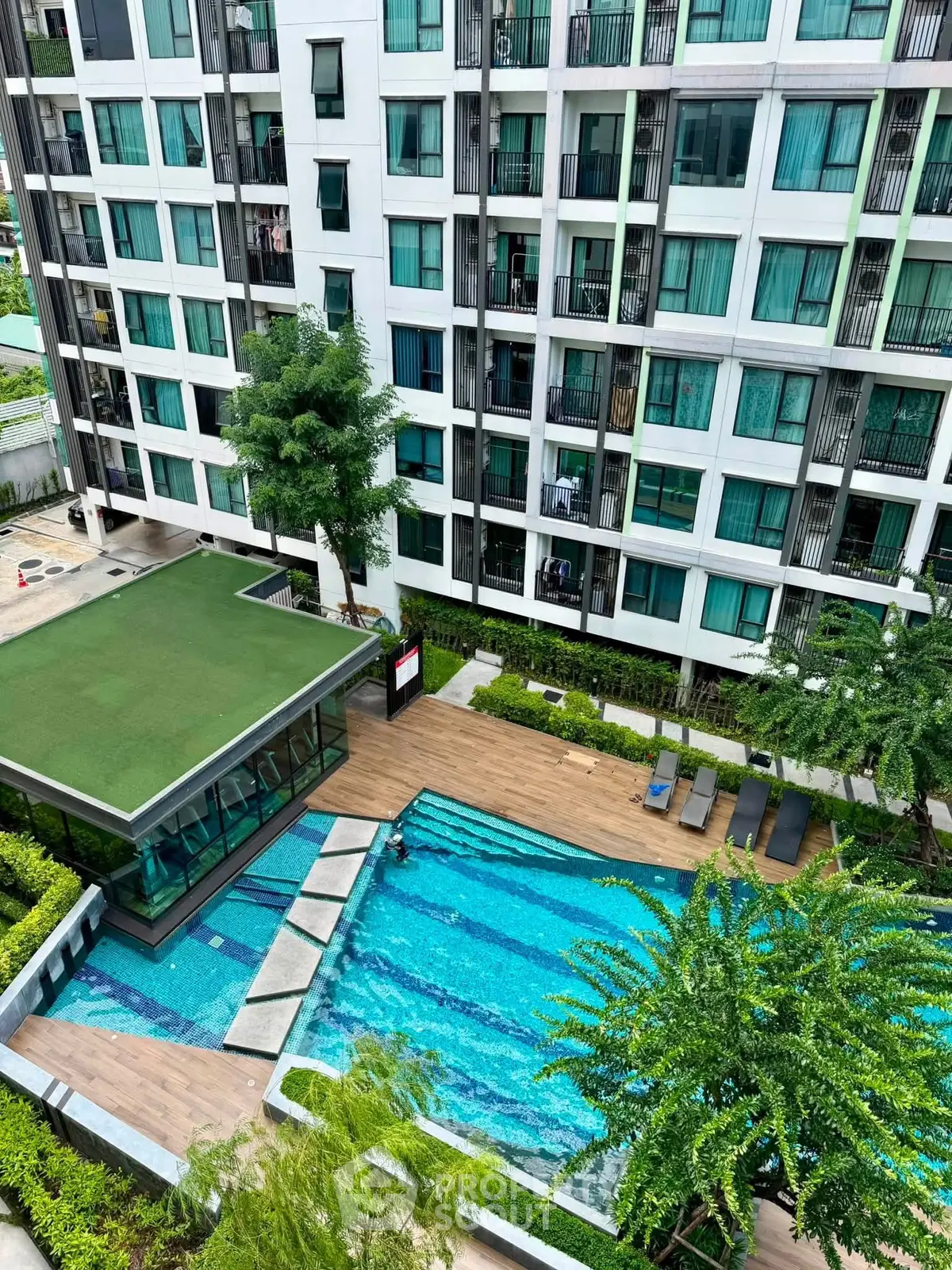 Modern apartment building with a stunning outdoor pool and lush greenery, perfect for urban living.