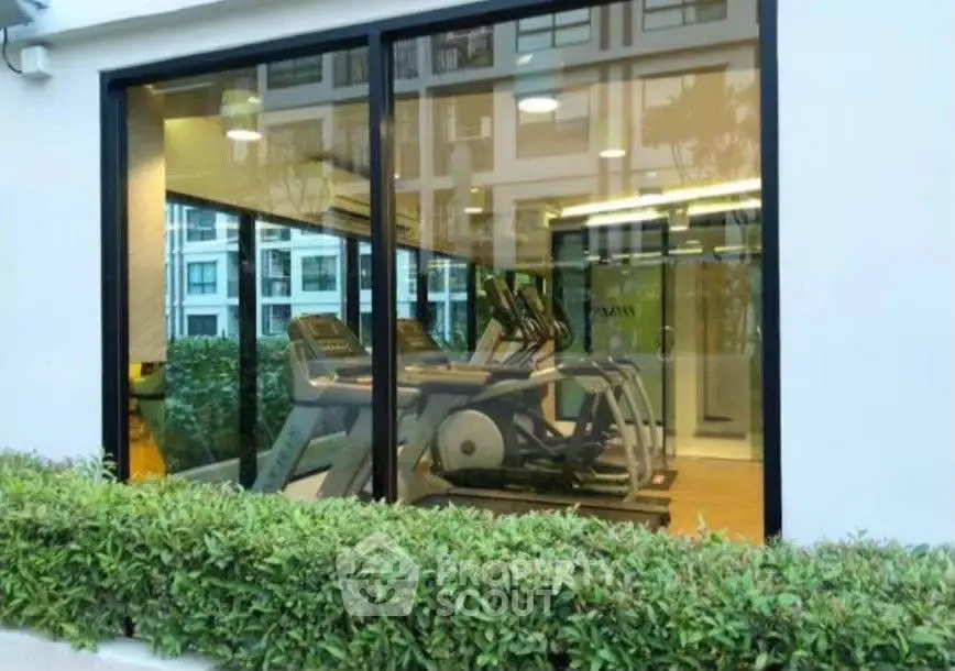Modern gym with large windows and exercise equipment in a residential building.