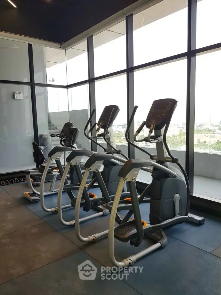 Modern gym with exercise equipment and large windows offering a scenic view.