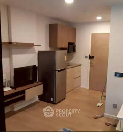 Modern compact kitchen with fridge and microwave in cozy apartment