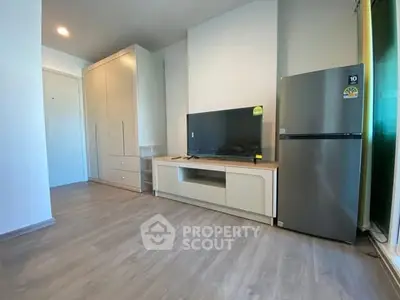 Modern living room with sleek TV unit and large fridge, showcasing minimalist design.