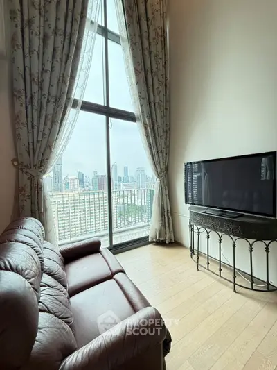 Spacious living room with large window offering stunning city view and elegant decor.