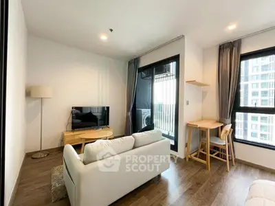Modern living room with cozy seating and large windows in a high-rise apartment.