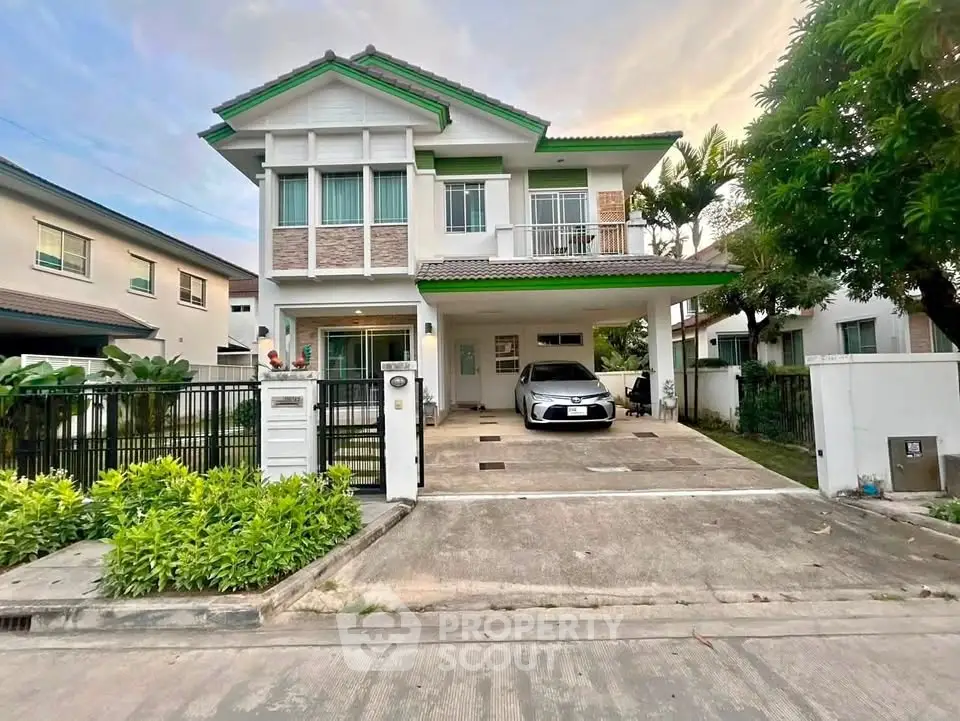Charming two-story house with driveway and lush greenery in a serene neighborhood.