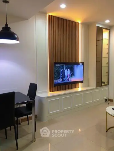 Modern living room with sleek TV setup and elegant dining area.