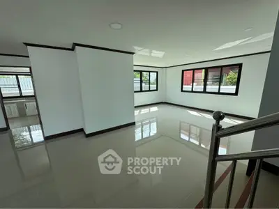 Spacious modern living room with large windows and glossy tiled floors, offering abundant natural light.