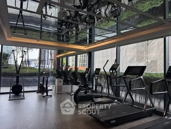 Modern gym with state-of-the-art equipment and floor-to-ceiling windows offering lush garden views.