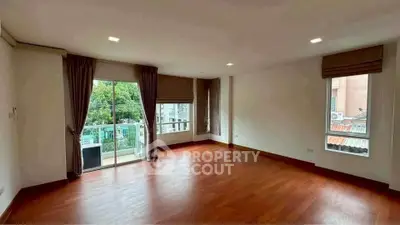 Spacious empty living room with hardwood floors and large windows for natural light.