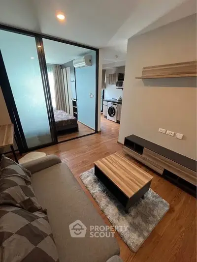 Modern apartment interior with cozy living room and view into bedroom and kitchen.