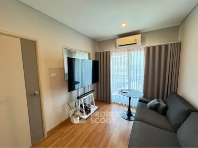Modern living room with large TV, cozy sofa, and balcony view in stylish apartment.