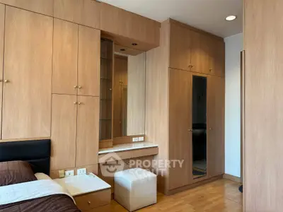 Spacious bedroom with built-in wooden wardrobes and cozy seating area.
