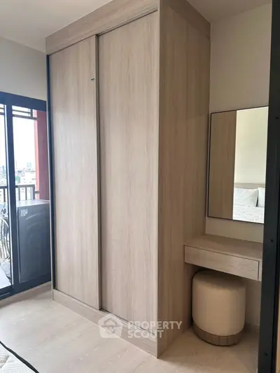 Modern bedroom with sleek wooden wardrobe and cozy vanity area, perfect for stylish urban living.