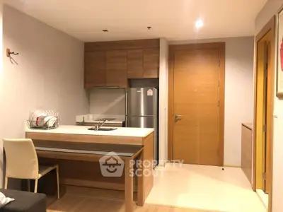 Modern kitchen with wooden cabinets and stainless steel fridge in cozy apartment.